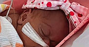 Alma is registered to the contest to win money with this photo: baby, blanket, child, closeup, crib, cute, face, headband, healthcare, hospital, indoors, infant, medical_tube, newborn, person, pink, resting, sleeping, soft, strawberry