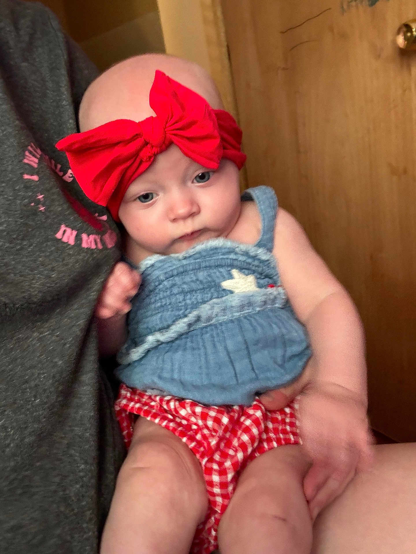 Amora joined the competition — help win amazing prizes! baby, child, red_bow, blue_top, red_checkered_bottoms, indoor, door, person, skin, hand, arm, face, head, clothing, holding, seated, close_up, casual, cute, infant
