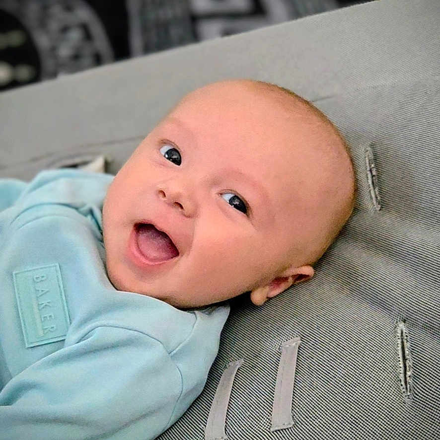 Teddie joined the competition — help win amazing prizes! baby, baby_garment, blue_clothing, child, closeup, comfort, cushion, cute, expression, face, happy, head, indoors, infant, lying_down, portrait, skin, smiling, texture, young