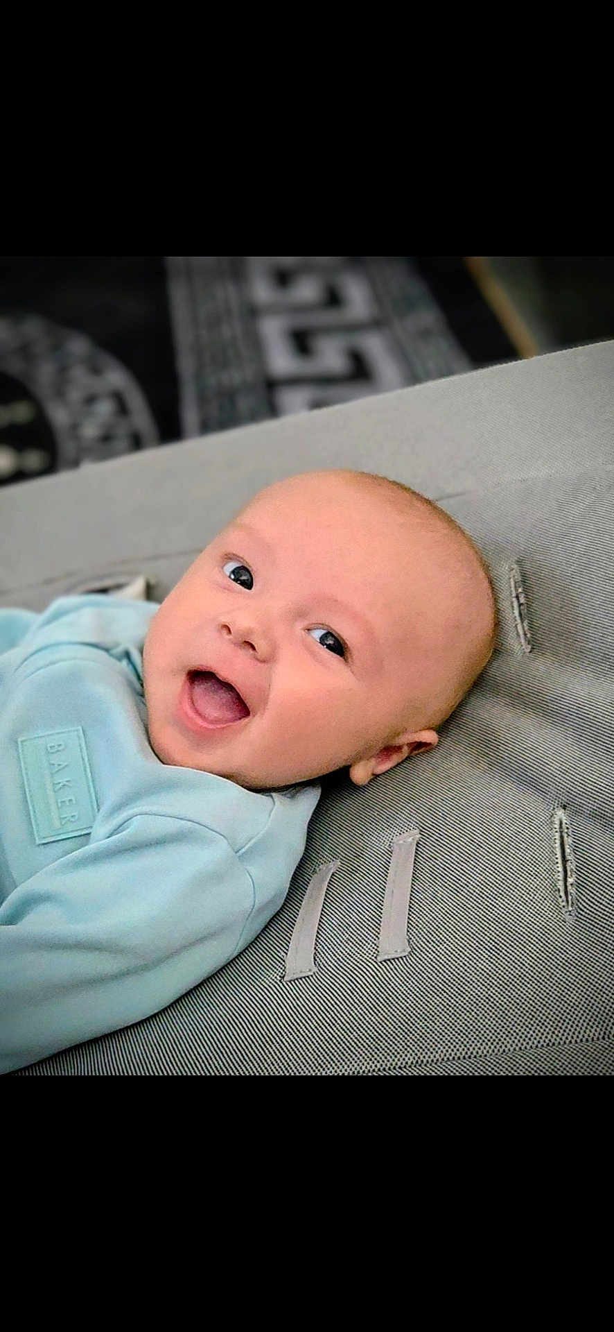 Teddie joined the competition — help win amazing prizes! baby, infant, smiling, happy, face, head, blue_clothing, cushion, texture, lying_down, closeup, skin, cute, child, young, portrait, indoors, comfort, expression, baby_garment