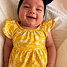 baby, child, smiling, yellow_dress, headband, bow, infant, portrait, happy, cute, lying_down, white_background, clothing, person, skin, face, hand, baby_fashion, indoors, young_child