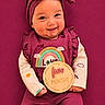 baby, infant, smiling, headband, magenta, outfit, sign, five_months, cute, portrait, child, indoors, happy, sitting, colorful, clothing, hands, face, background, celebration