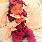 Alaina joined the competition — help win amazing prizes! baby, infant, child, headband, maroon_outfit, plaid, wooden_plaque, milestone, cushion, white_background, cute, curious, hands, sitting, indoors, portrait, soft_lighting, clothing, cozy, young_child