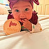 baby, infant, headband, bed, sign, milestone, fingers, cute, portrait, lying_down, indoors, colorful_clothing, child, young, smiling, face, person, closeup, celebration, warm_lighting