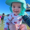 baby, child, smiling, hat, sun_hat, outdoor, water, boat, blue_sky, person, summer, playful, american_flag, clothing, face, happy, closeup, skin, people, nature