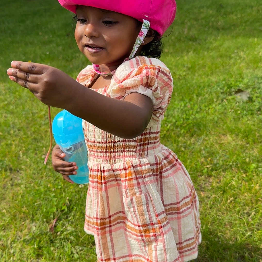 Asuna is registered to the contest to win money with this photo: child, curious, daylight, dress, exploring, footwear, grass, greenery, hat, nature, outdoor, park, person, playful, smiling, summer, sunlight, toddler, tree, water_bottle