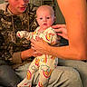 baby, child, person, man, indoor, pajamas, rainbow, clothing, holding, supporting, family, couch, sitting, hands, face, expression, young_adult, casual, home, comfort