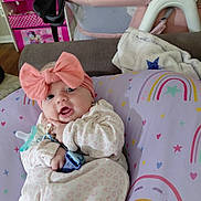 Willow joined the competition — help win amazing prizes! baby, infant, pink_bow, pacifier, pillow, rainbow_pattern, stars, hearts, blanket, couch, clothing, face, person, indoor, cute, child, headband, smile, happy, soft_toys