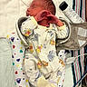 newborn, baby, infant, sleeping, portrait, onesie, clothing, hands, face, hair, hospital, changing_bag, medical_supplies, blanket, hearts, patterned, striped_fabric, lying_down, indoors, photography