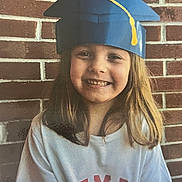 Lilliaunna joined the competition — help win amazing prizes! blue_cap, brick_wall, casual_clothing, celebration, child, cute, face, fun, girl, graduation_cap, happy, headwear, long_hair, outdoor, person, portrait, smiling, white_shirt, yellow_tassel, young