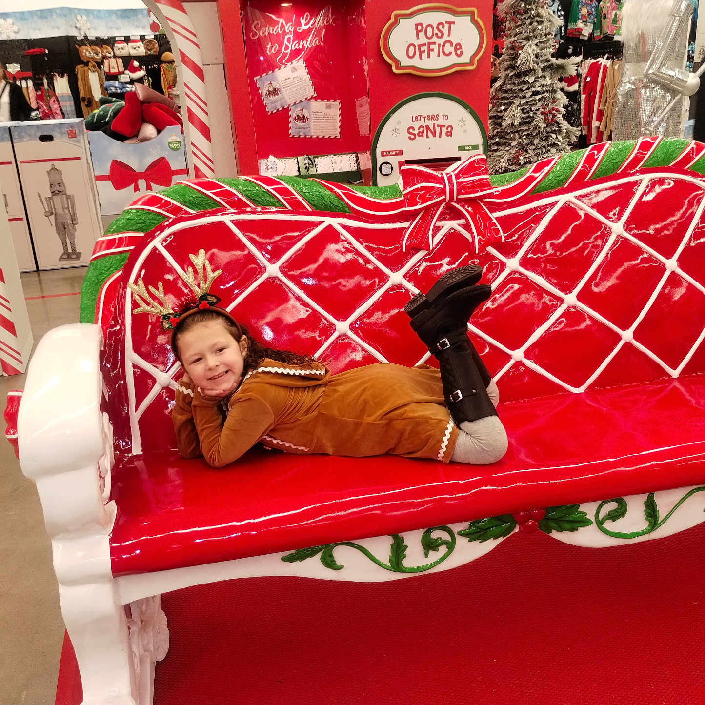 Addasyn is registered to the contest to win money with this photo: antlers, bench, boots, child, christmas, costume, decorations, festive, floor, green, happy, holiday, indoor, person, red, seasonal, shopping, smiling, store, toy