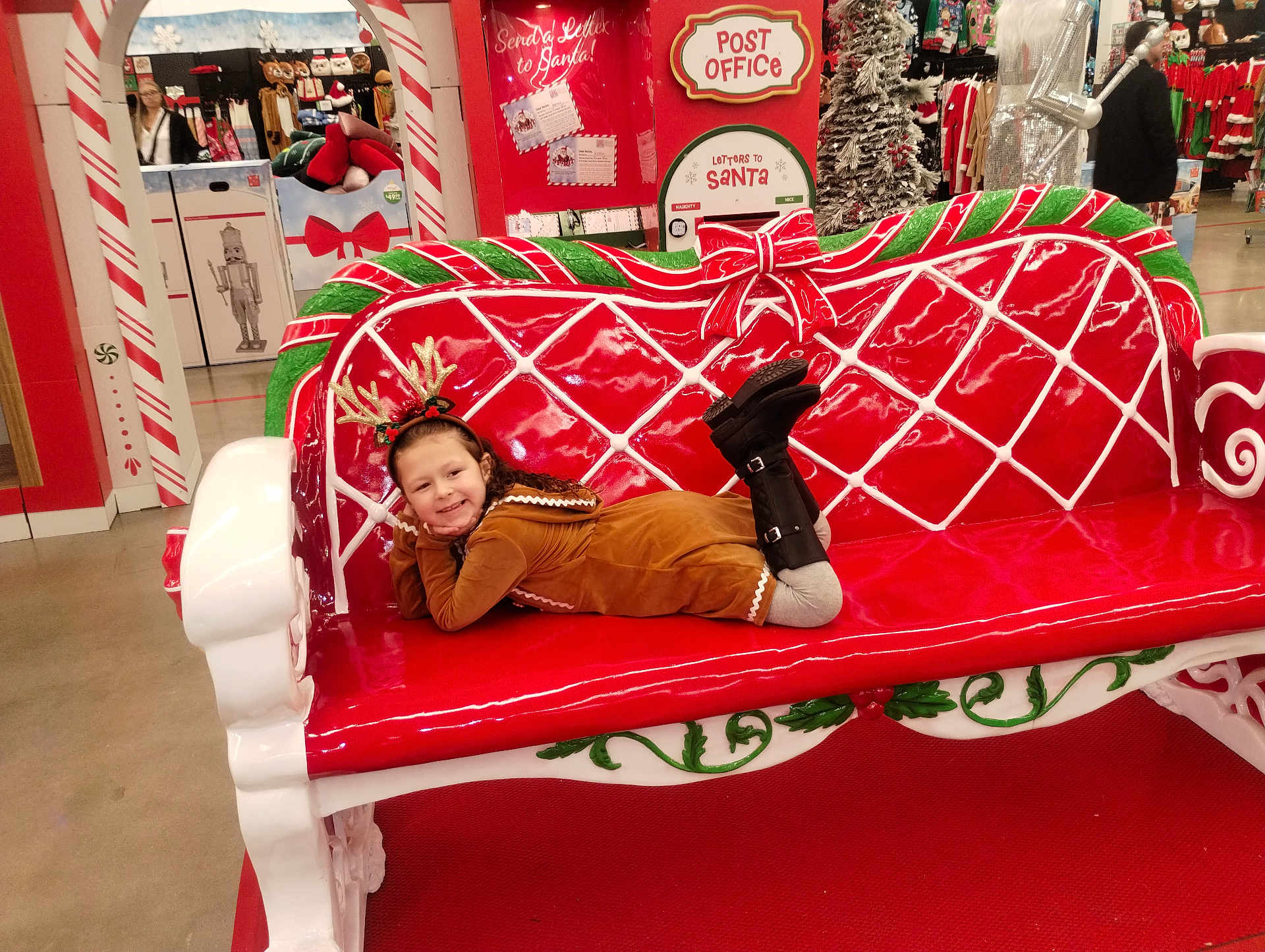 Addasyn is registered to the contest to win money with this photo: child, smiling, holiday, christmas, bench, red, green, antlers, costume, store, shopping, decorations, festive, indoor, person, boots, floor, toy, seasonal, happy