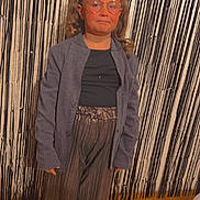 Lou-Ann a rejoint le concours — aidez-le/la à gagner de superbes lots ! child, girl, portrait, glasses, curly_hair, jacket, t_shirt, wide_leg_pants, shiny_pants, sneakers, party_backdrop, foil_curtain, gold_balloon, balloon_frame, floor_tiles, indoor, standing, posed, celebration, neutral_expression