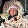 baby, infant, car_seat, blanket, pink_bow, sleeping, toy, pacifier, soft_toy, floral_pattern, cozy, headband, child, cute, resting, indoors, comfort, smiling, wrapped, peaceful