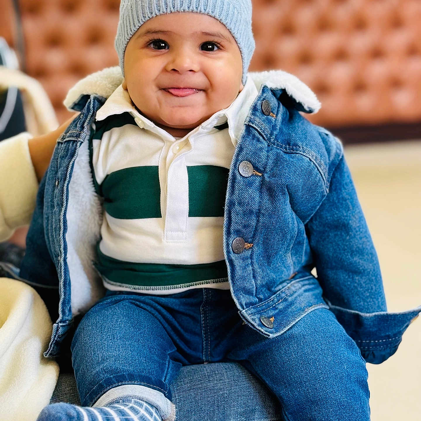 Abeer is registered to the contest to win money with this photo: baby, casual_wear, child, closeup, cozy_clothing, cute, denim_jacket, fashion, happy, indoor, jeans, knit_hat, person, portrait, seated, smiling, striped_sock, toddler, tongue_out, warm