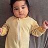baby, child, infant, portrait, lying_down, couch, indoors, yellow, striped_clothing, romper, zipper, dark_hair, brown_eyes, face, hands, calm, cute, soft_lighting, furniture, cozy