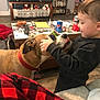 Sadie And Brook is registered to the contest to win money with this photo: blanket, book, can, child, dog, floor, furniture, home, indoor, living_room, person, pet, playing, red_collar, remote_control, sofa, sunglasses, table, toy, wooden_floor