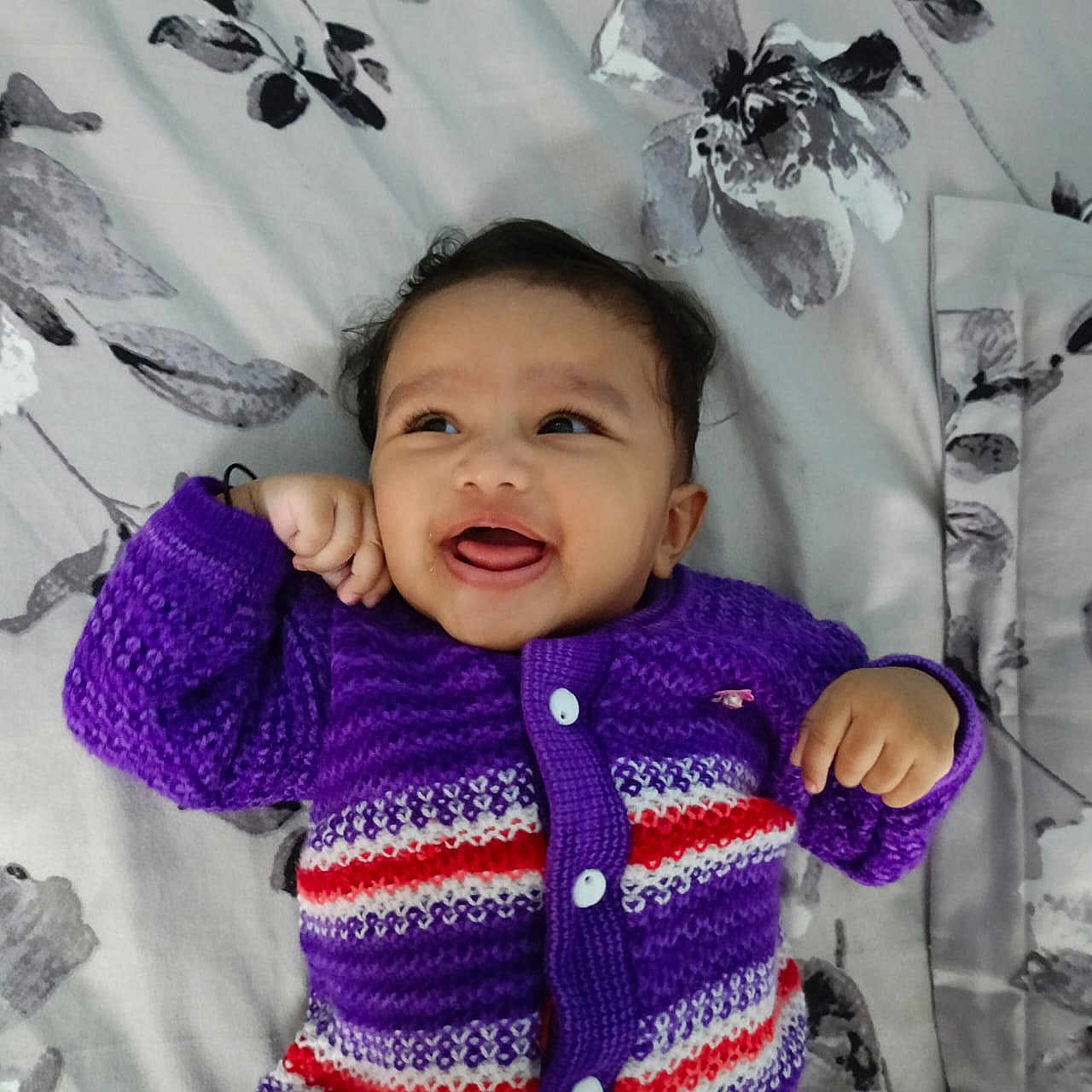 Neeharika joined the competition — help win amazing prizes! baby, bedspread, buttoned_sweater, cheerful, child, close_up, cozy, cute, face, floral_pattern, happy, indoors, infant, knitted_clothing, lying_down, portrait, purple_sweater, small_hands, smiling, warm