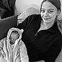 Khalifa a rejoint le concours — aidez-le/la à gagner de superbes lots ! baby, child, woman, smile, couch, blanket, hooded_onesie, indoor, portrait, holding, sleeping, cozy, black_and_white, casual_clothing, young_adult, face, person, relaxing, comfort, home