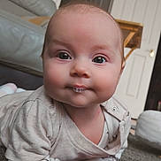 Lilith is registered to the contest to win money with this photo: baby, infant, face, eyes, bubble, carpet, home_interior, furniture, door, wood, clothing, tummy_time, cute, child, indoor, portrait, skin, expression, person, cozy