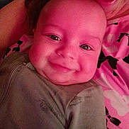 Dakota joined the competition — help win amazing prizes! baby, smile, face, infant, closeup, eyes, clothing, blanket, pattern, pink, grey, person, child, cute, happy, portrait, indoors, skin, young, lying_down