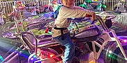 Willie is registered to the contest to win money with this photo: amusementpark, boy, child, clothing, face, footwear, head, indoors, lighting, machine, male, motorcycle, person, playarea, shoe, sphere, spoke, transportation, vehicle, wheel