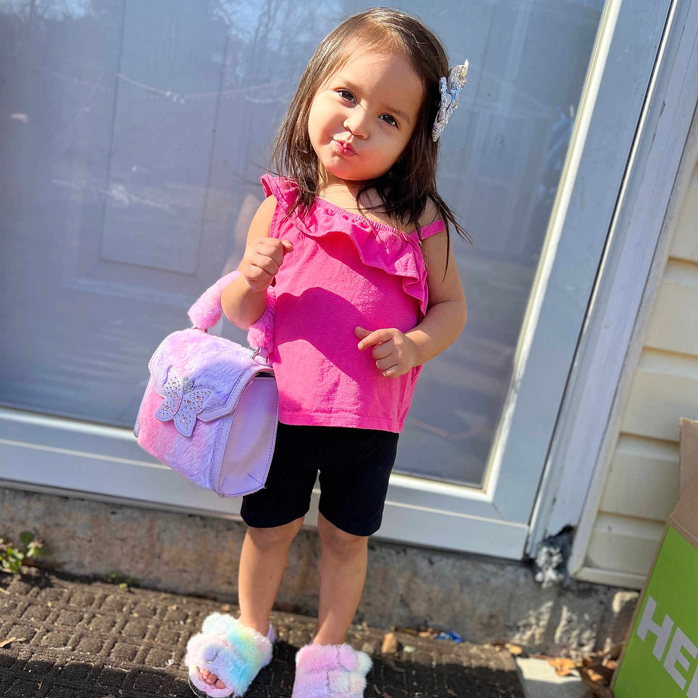 Kelahnie joined the competition — help win amazing prizes! accessory, black_shorts, child, cute, door, fashion, fluffy_slippers, footwear, girl, hair_clip, handbag, outdoor, pavement, pink_top, playful, posing, sidewalk, smiling, standing, sunlight