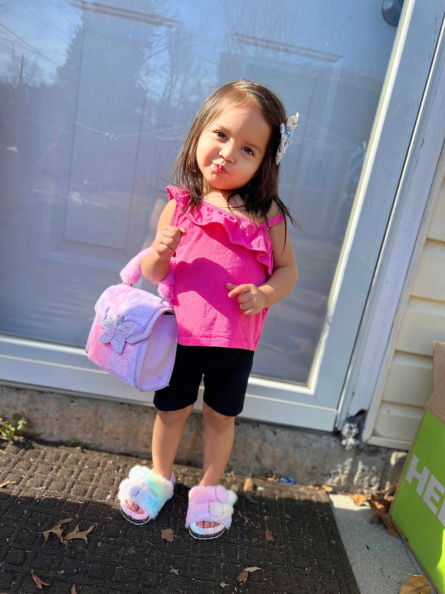 Kelahnie joined the competition — help win amazing prizes! child, girl, pink_top, black_shorts, handbag, fluffy_slippers, standing, outdoor, door, pavement, sunlight, playful, posing, hair_clip, smiling, cute, fashion, accessory, footwear, sidewalk