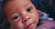 Orrian is registered to the contest to win money with this photo: baby, infant, child, portrait, face, wide_eyes, looking_at_camera, lying_down, arms, hands, skin, indoor, bedroom, curtain, patterned_background, soft_lighting, close_up, cozy, photography, cute