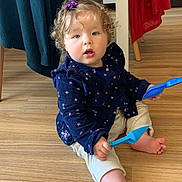 Louise a rejoint le concours — aidez-le/la à gagner de superbes lots ! toddler, child, curly_hair, hair_clip, blue_shovel, plastic_toy, sitting, wooden_floor, indoor, clothing, pants, long_sleeve, purple, red_cloth, chair, foot, hand, face, expression, home