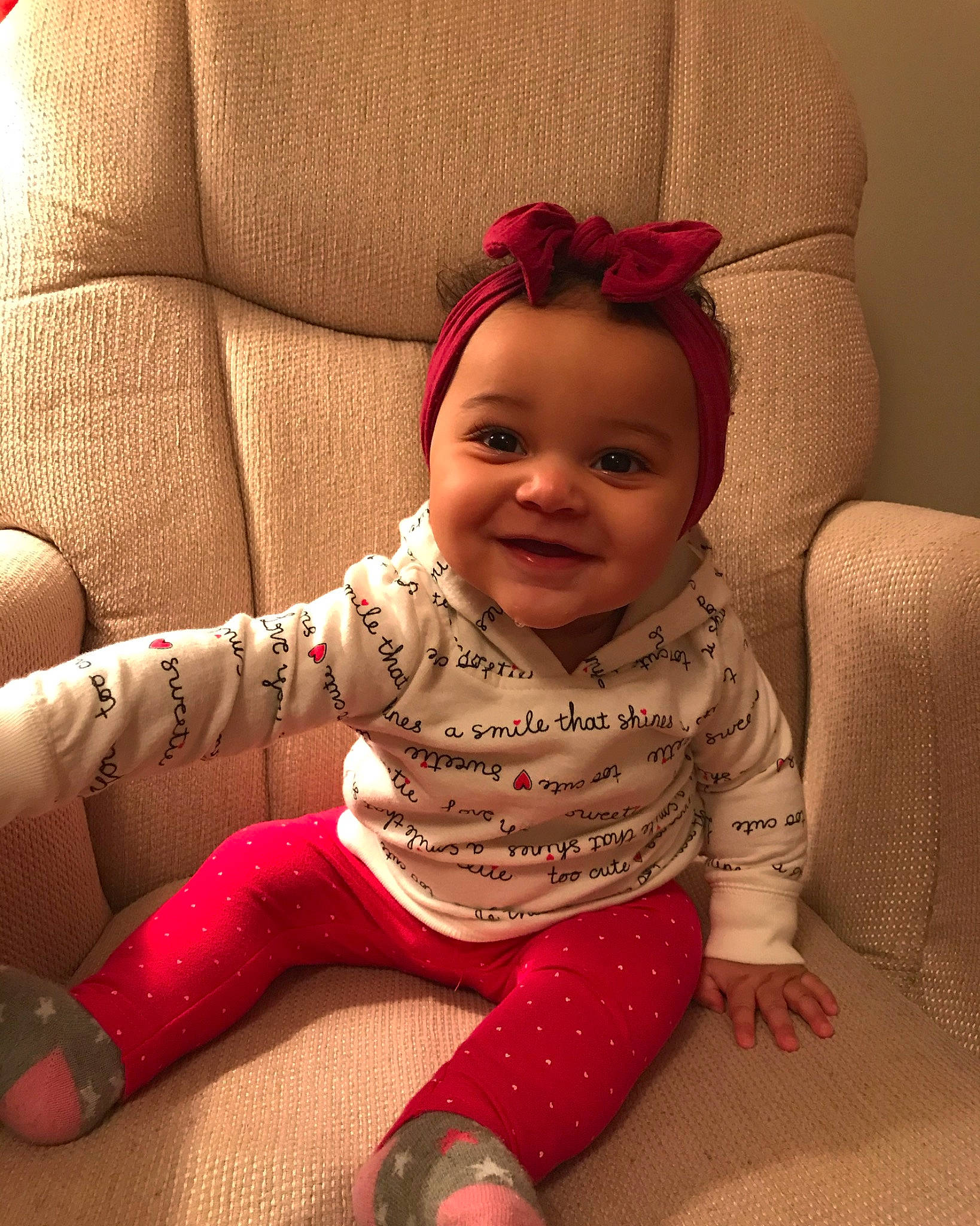 Jaida is registered to the contest to win money with this photo: arm, baby, baby_toddler_clothing, cheek, child, ear, face, head, joy, leg, lip, person, pink, sitting, skin, sleeve, smile, toddler