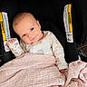 baby, infant, blue_eyes, smile, blanket, car_seat, clothing, hand, face, head, person, cute, newborn, indoors, fabric, seat, warning_label, child, cozy, portrait