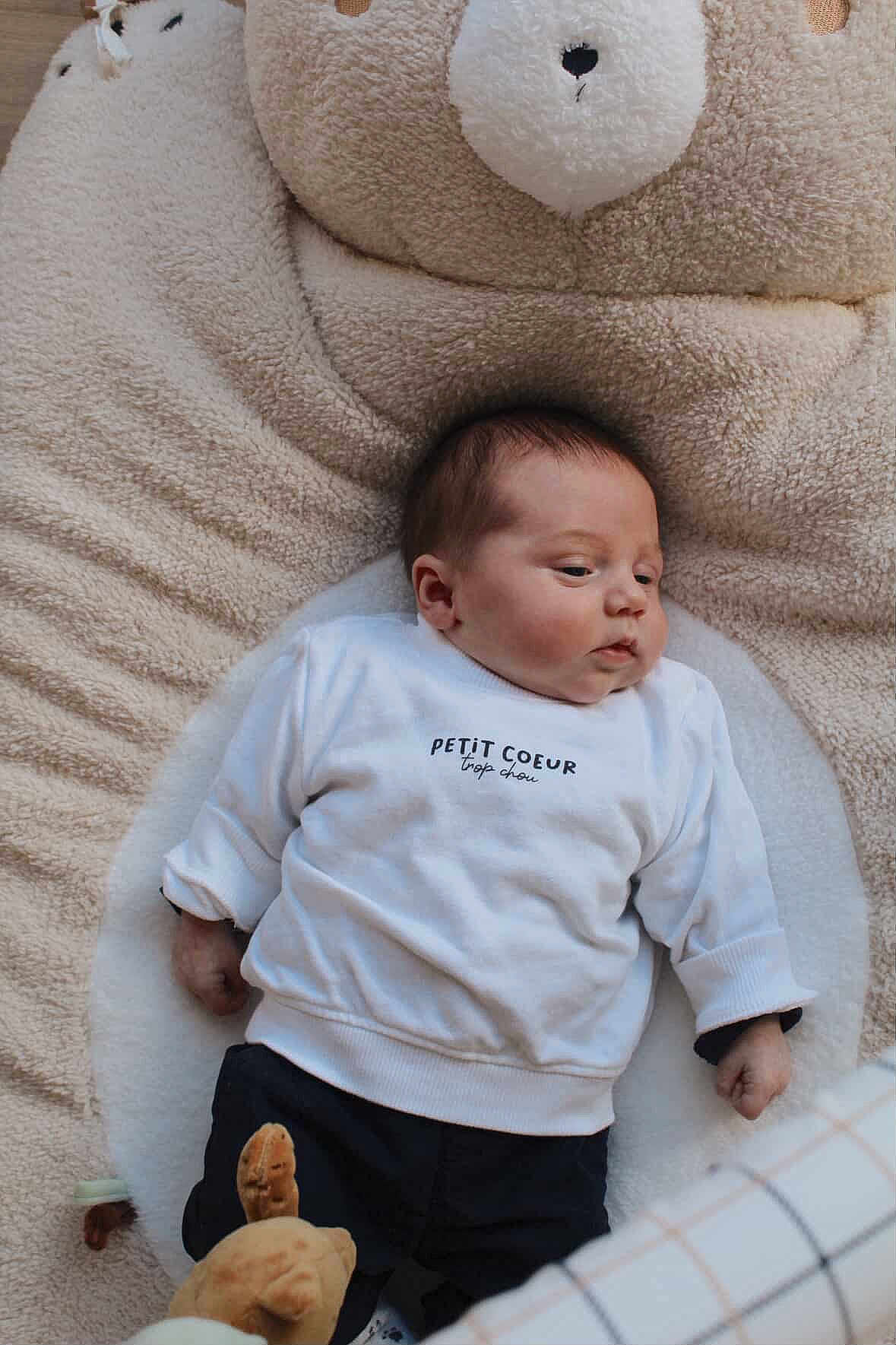 Victor a rejoint le concours — aidez-le/la à gagner de superbes lots ! baby, infant, newborn, face, teddy_bear, plush, blanket, onesie, clothing, pillow, head, hand, laying, nursery, soft_texture, portrait, cute, cozy, toy, indoor