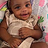 baby, child, infant, smiling, portrait, bow, headband, dress, sitting, lying_down, blanket, playmat, patterned_background, indoor, face, hands, legs, happy, cute, photography