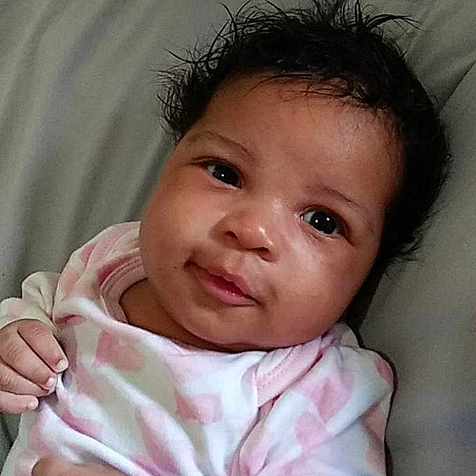 Winter joined the competition — help win amazing prizes! baby, infant, child, lying_down, pillow, onesie, pink, white, curly_hair, face, smile, looking_at_camera, young_child, indoors, cute, portrait, skin, hand, head, expression