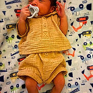 Juan is registered to the contest to win money with this photo: baby, newborn, pacifier, blanket, clothing, infant, cute, patterned_blanket, socks, lying_down, child, small_hands, soft_texture, adorable, portrait, sleepwear, indoors, resting, human, warm_clothing