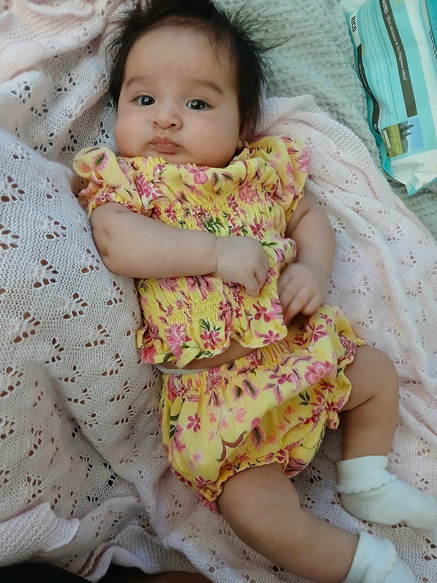 Ahtziri joined the competition — help win amazing prizes! baby, infant, child, yellow_clothing, floral_pattern, blanket, knitted_blanket, soft_texture, cute, chubby_cheeks, lying_down, white_socks, indoors, portrait, face, curious_expression, small_hands, soft_lighting, relaxed, cozy