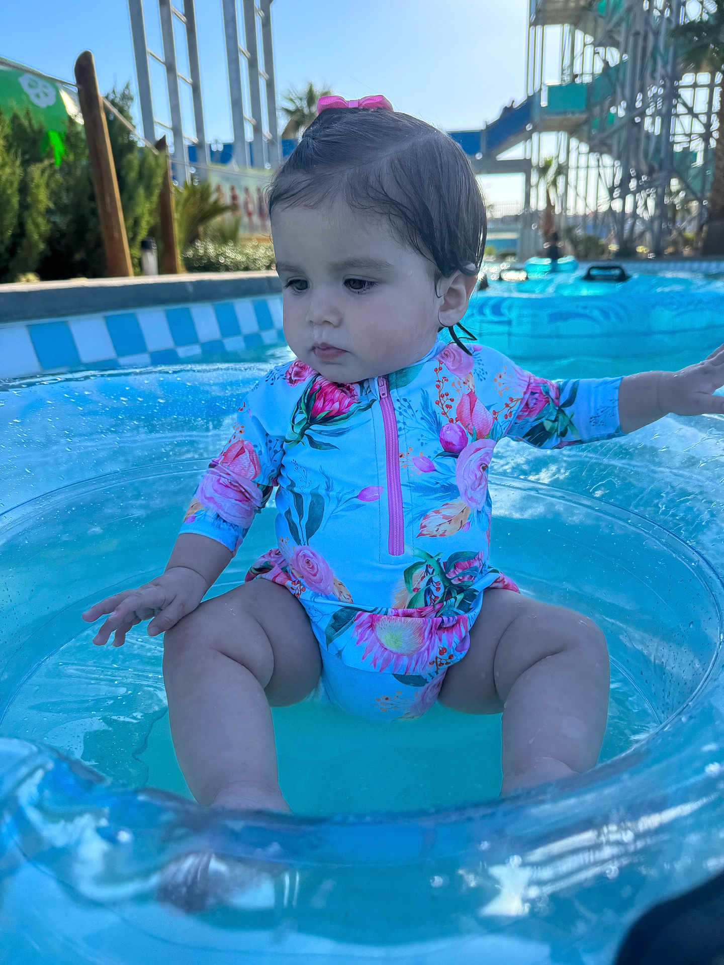Kaitlyn joined the competition — help win amazing prizes! toddler, child, swimsuit, inflatable_ring, pool, water, water_park, slide, outdoor, sunny, summer, palm_tree, floating, baby, sitting, cute, colorful, water_fun, playful, vacation