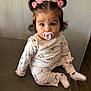 Kaitlyn is registered to the contest to win money with this photo: baby, child, pacifier, pink_bows, pajamas, floral_pattern, sitting, wooden_surface, curious_expression, indoor, cute, hair_buns, long_sleeves, socks, floor, wall, portrait, young_child, person, toddler