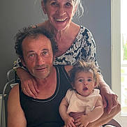 Lucia participe au concours pour gagner de l'argent avec cette photo : family, indoor, baby, man, woman, smile, surprised, expression, holding, seated, standing, window, natural_light, casual_clothing, hair, hand, furniture, trash_can, domestic, portrait