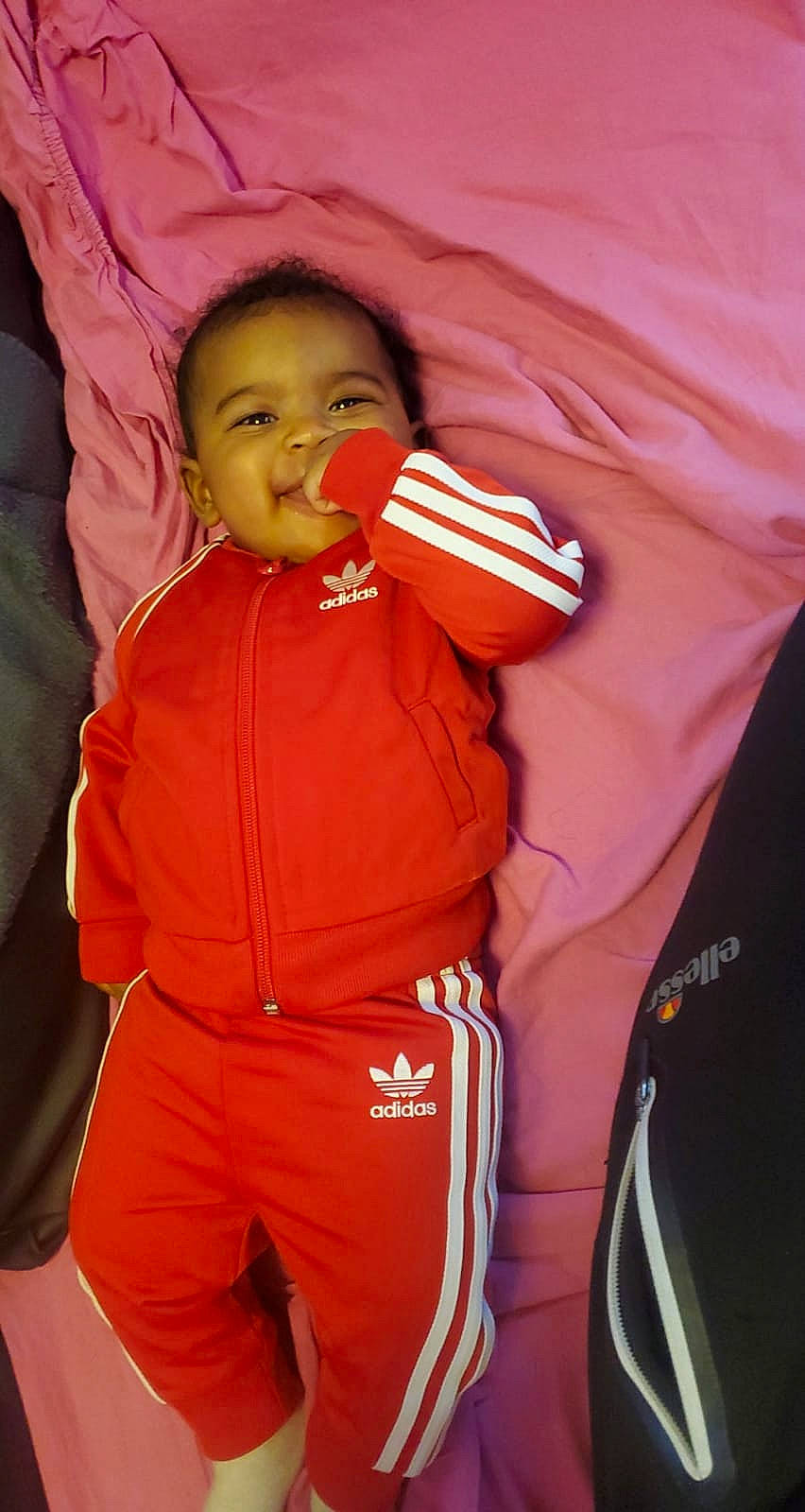 Lya participe au concours pour gagner de l'argent avec cette photo : baby, baby_toddler_clothing, carmine, child, comfort, gesture, happy, human_body, lifejacket, orange, outerwear, peach, person, personal_protective_equipment, sleeve, t_shirt, thumb, toddler, uniform, workwear