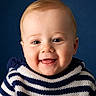 baby, smiling, portrait, child, blue_background, striped_sweater, cute, happy, face, infant, young_child, sitting, studio_photo, closeup, headshot, person, indoors, light_skin, short_hair, casual_clothing