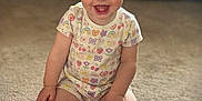 Raelynn is registered to the contest to win money with this photo: toddler, child, smile, happy, carpet, sitting, onesie, colorful_clothing, indoor, living_room, face, baby, cute, short_hair, bright_eyes, fun, playful, person, couch, background