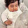 baby, curly_hair, white_outfit, stars, balloon, lights, hand, face, infant, cute, soft_fabric, closeup, indoors, child, smile, expression, portrait, cozy, newborn, blanket