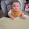 Dayton is registered to the contest to win money with this photo: baby, high_chair, bib, infant, child, indoor, kitchen, face, person, furniture, table, expression, curious, home, sitting, young_child, skin, clothing, feeding, domestic