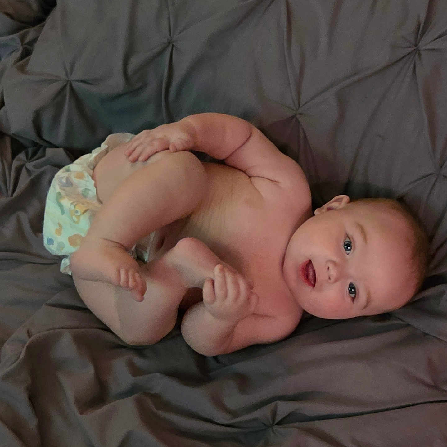 Dayton is registered to the contest to win money with this photo: baby, diaper, infant, child, skin, bedspread, fabric, smile, hand, foot, lying_down, cute, playful, person, young_child, room, indoor, resting, expression, human
