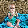 baby, child, swimsuit, towel, rocky_ground, messy, cream, face, hands, legs, blue, turquoise, sitting, outdoor, cute, small_cup, curious, person, summer, playful