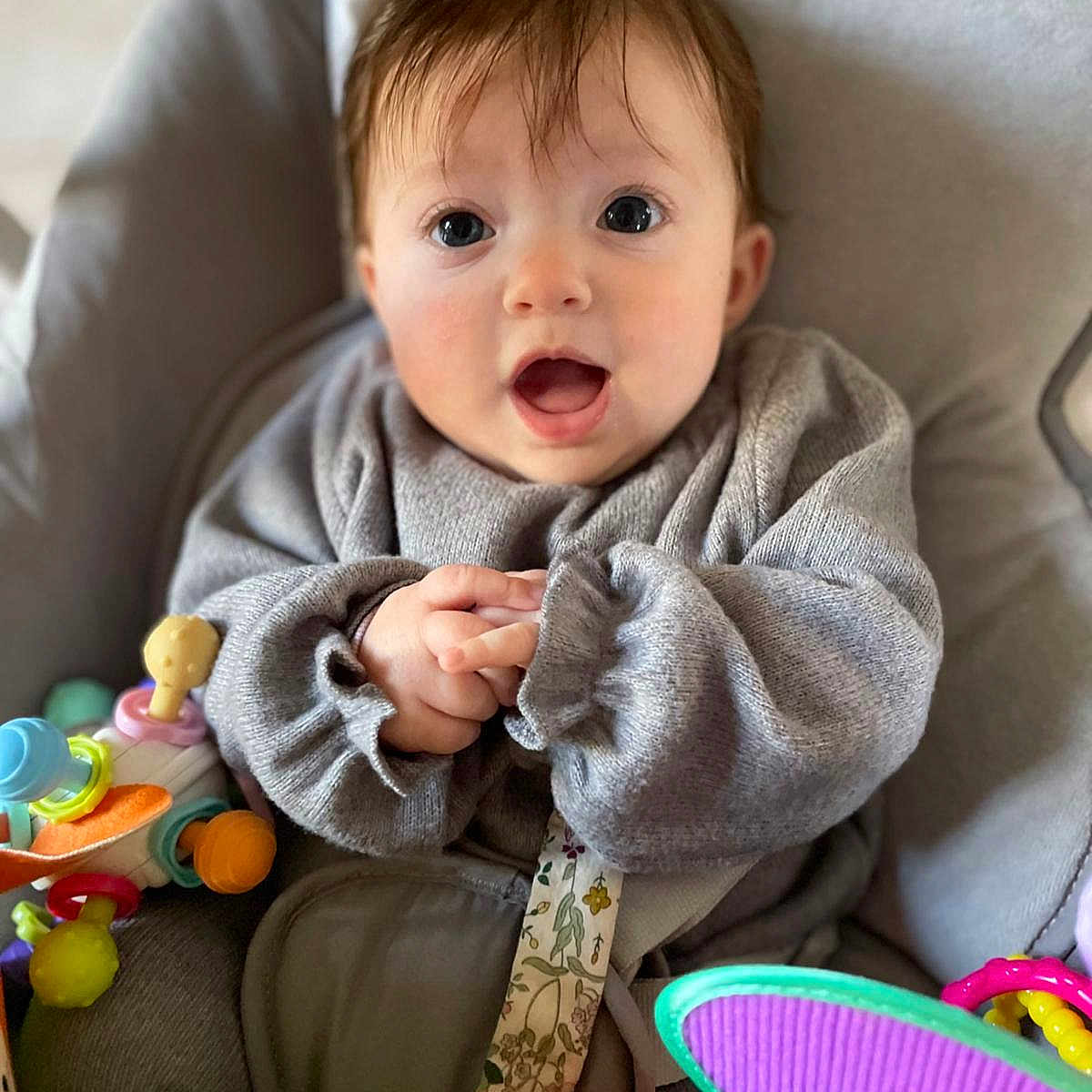 Louison a rejoint le concours — aidez-le/la à gagner de superbes lots ! baby, child, infant, gray_sweater, seat, toy, colorful, hand, face, expression, wide_eyes, cushion, indoor, clothing, person, cute, small_hands, happy, closeup, portrait