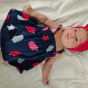 Addilyn is registered to the contest to win money with this photo: baby, infant, child, dress, headband, bow, navy_blue, red, popsicle_print, lying_down, white_background, cute, soft, skin, arms, legs, clothing, portrait, indoors, curious