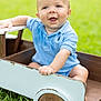 baby, child, blue_shirt, wooden_toy, toy_car, grass, outdoor, smiling, happy, face, drool, greenery, cute, sitting, play, sunlight, portrait, infant, nature, casual_clothing